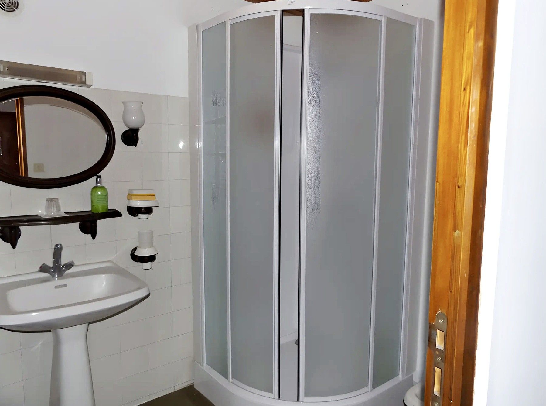 A bathroom with a white sink, a mirror, and a glass-enclosed shower.