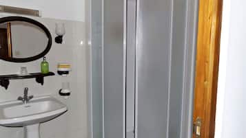 A bathroom with a white sink, a mirror, and a glass-enclosed shower.