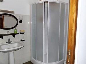 Een badkamer met een witte wastafel, een spiegel en een douche met glazen wanden.