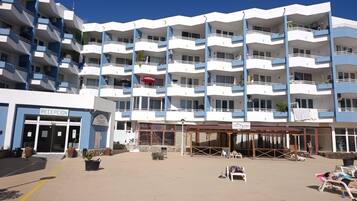 Een meerlaags hotel met een receptie, terras en balkons.
