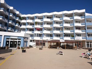 Een meerlaags hotel met een receptie, terras en balkons.