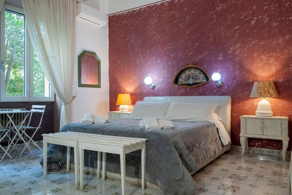Un dormitorio con cama, mesitas de noche, cortinas y vistas a zonas verdes.