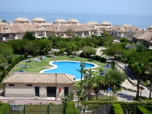 Un quartier résidentiel doté d’une piscine, de chaises longues et offrant une vue sur la mer.