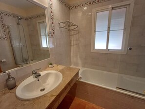 Ein Badezimmer mit Waschbecken, Spiegel, Dusche und Fenster.