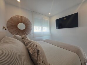 Ein Schlafzimmer mit einem Bett, einem runden Spiegel, einem Fernseher und einem Fenster.