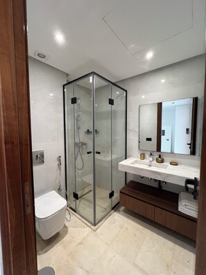 A modern bathroom with a glass-enclosed shower, a white toilet, a vanity with a mirror, and a wooden cabinet. - New Listing (Casablanca)