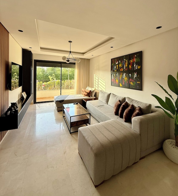 A modern living room with a sofa, a coffee table, and a TV mounted on the wall. - New Listing (Casablanca)