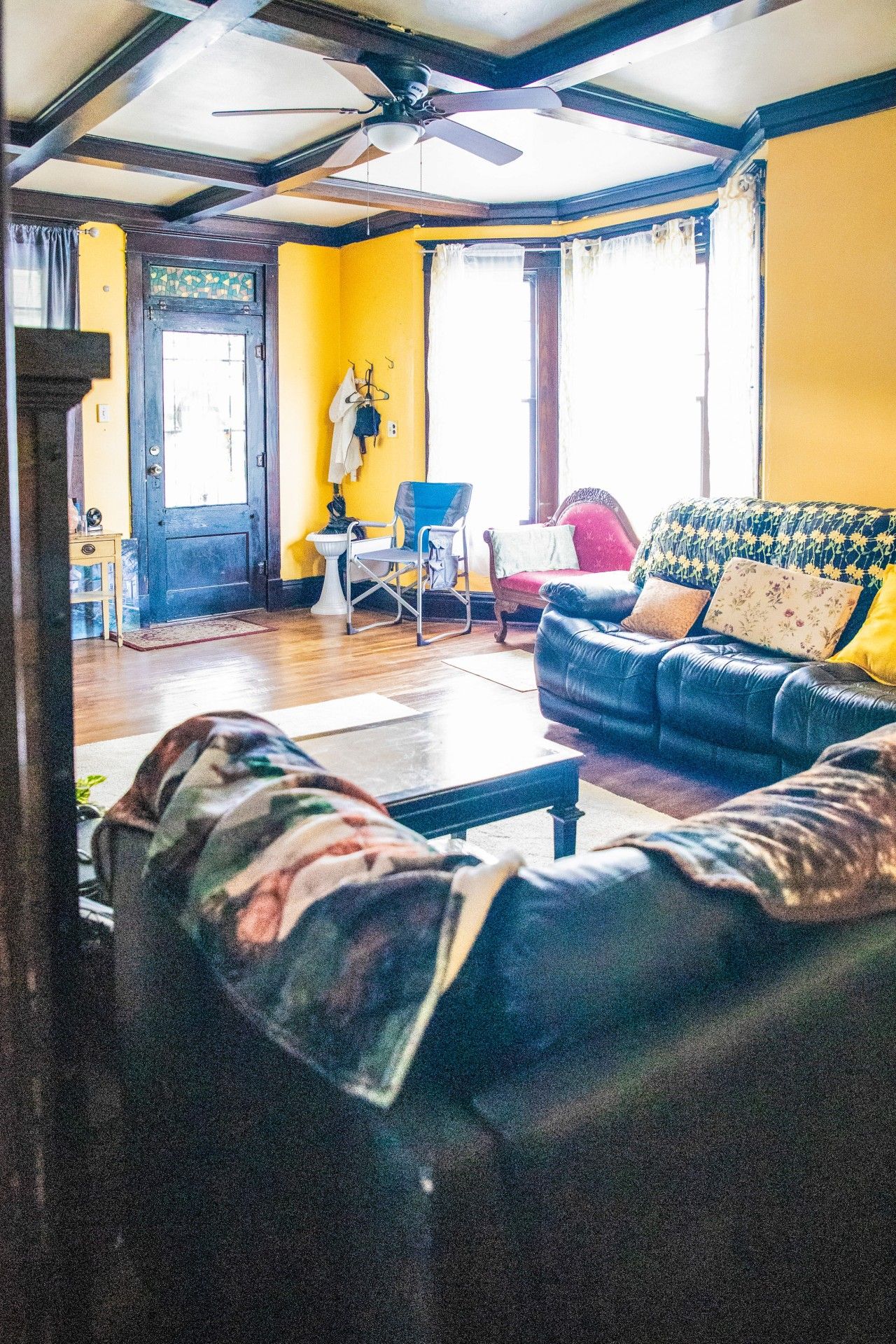 Una sala de estar con un sofá, un sillón y un ventilador de techo.
