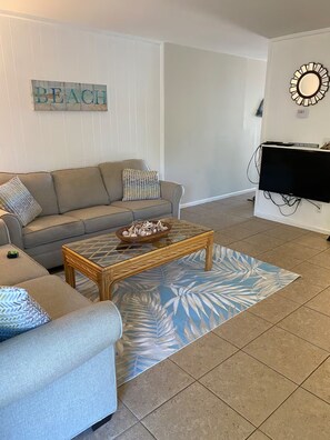 Uma sala de estar com sofá, mesa de centro e televisão.