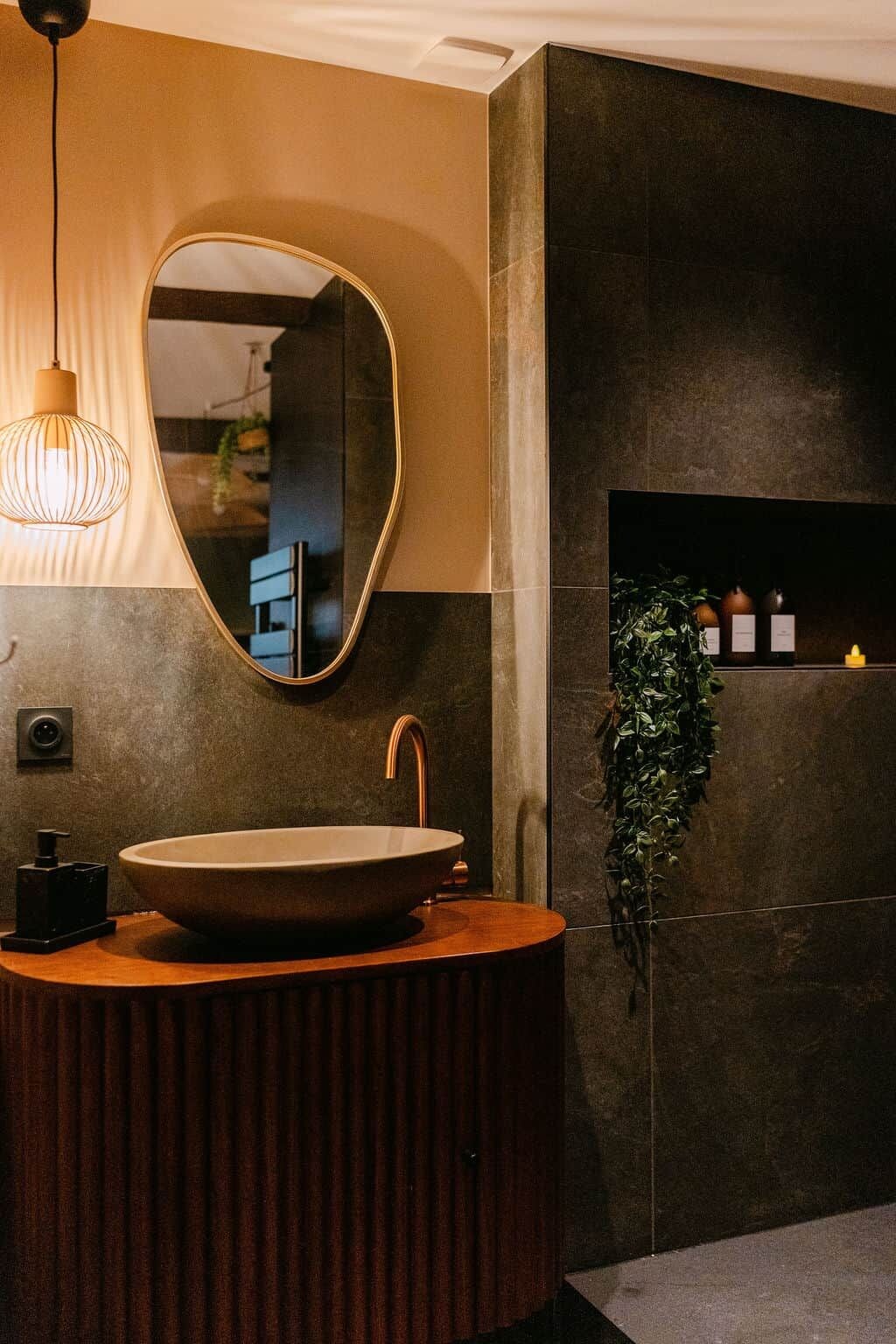 A modern bathroom with a round sink, a mirror, and a pendant light.