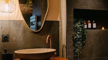 A modern bathroom with a round sink, a mirror, and a pendant light.