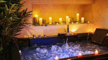 A spa area with a hot tub, candles, and a wall-mounted shelf with candles.
