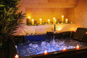 A spa area with a hot tub, candles, and a wall-mounted shelf with candles. - Mana Suite & Spa - Luxury & Wellness (Tarare)