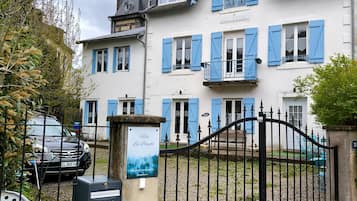 Monikerroksinen rakennus, jossa on siniset ikkunaluukut, portti ja kyltti, jossa lukee »Villa Les Bleus».