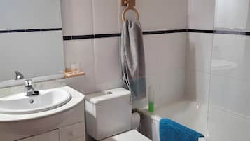 Een badkamer met toilet, wastafel en bad.