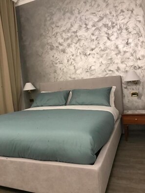 A bed with a headboard, two bedside lamps, and a nightstand with a lamp. - Sandel Giubileo Hotel (ROMA)