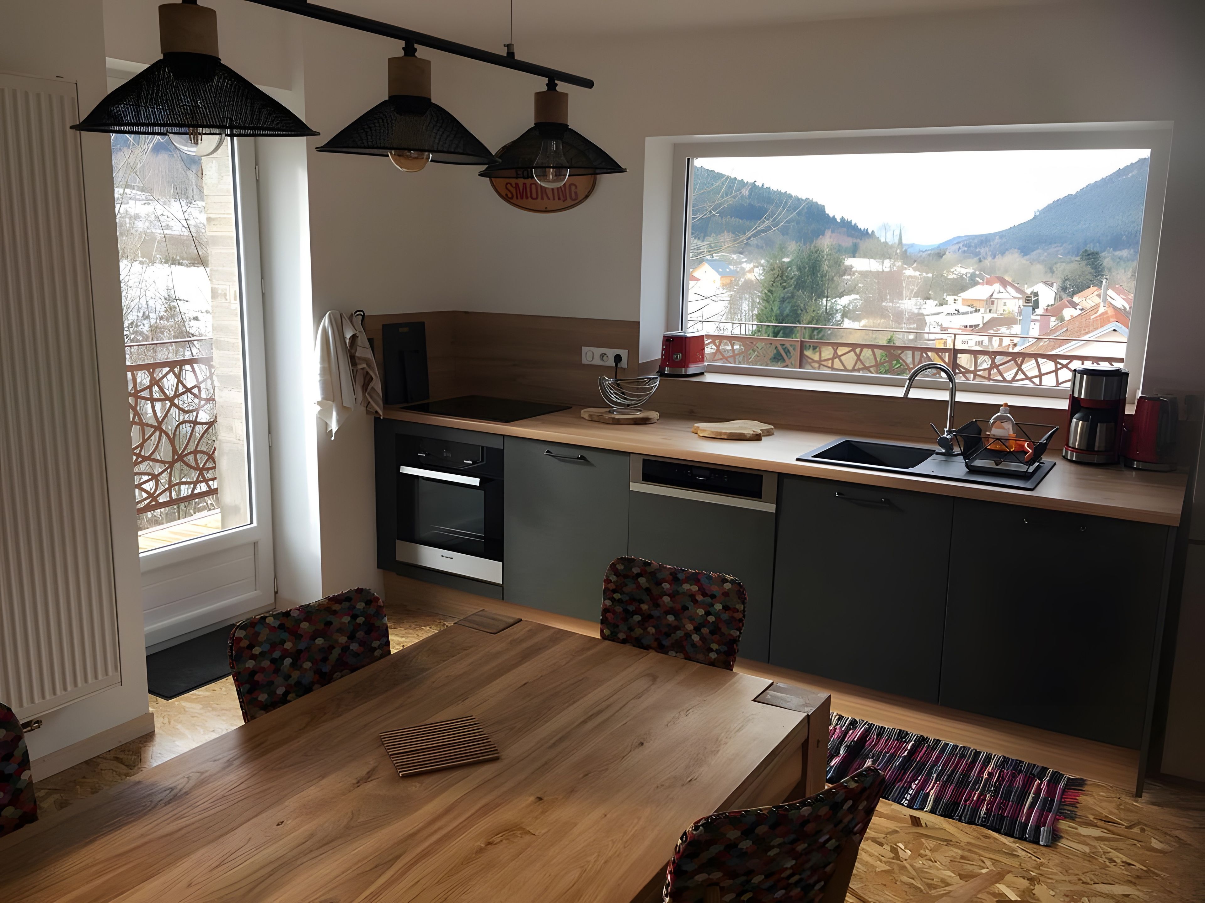 Une cuisine moderne avec une grande fenêtre, une table en bois et des chaises.