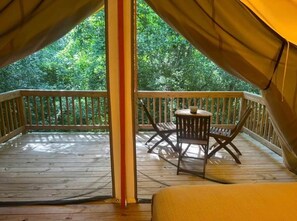 A tent with a wooden deck, a table, and chairs.