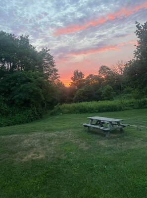 A picnic table in a grassy field with trees in the background.