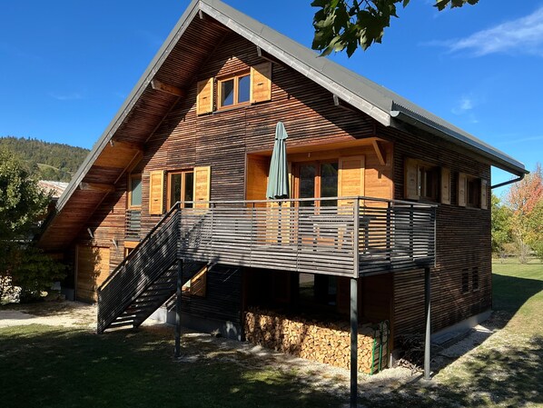 Une cabane en bois à deux étages, dotée d’un balcon et d’un escalier menant à l’étage supérieur.