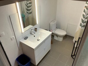 Une salle de bain avec un lavabo blanc, un miroir et des toilettes.