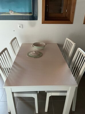 Une table à manger avec deux bols et un couvercle, entourée de chaises blanches.