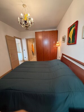 Ein Schlafzimmer mit einem großen Bett, einem Holzschrank, einer Chandelierleuchtre und einem gerahmten Bild an der Wand.
