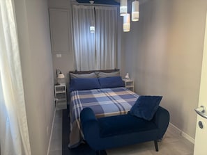 Une chambre à coucher avec un lit, une table de chevet, une lampe et un canapé bleu.
