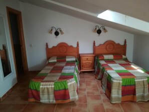A room with two beds, each with a colorful striped bedspread, a wooden nightstand, and a wall-mounted lamp between the beds. - Country House 'Casa Rural Valdecorneja' with Private Terrace (Hoyorredondo)