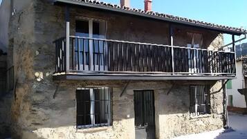 A two-story building with a balcony, a chimney, and a window with bars.