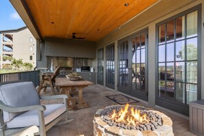 An outdoor patio with a fire pit, seating, and a kitchen area. - Crimson Waters at Hill House | Golf Cart Optional (Tuscaloosa)