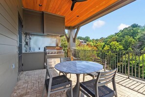 An outdoor patio with a grill, table, and chairs. - The Retreat at Hill House (Tuscaloosa)