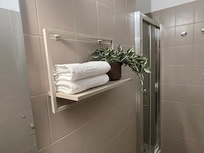 Un bagno con un portascopevoli pieno di asciugamani piegati e una pianta in vaso.