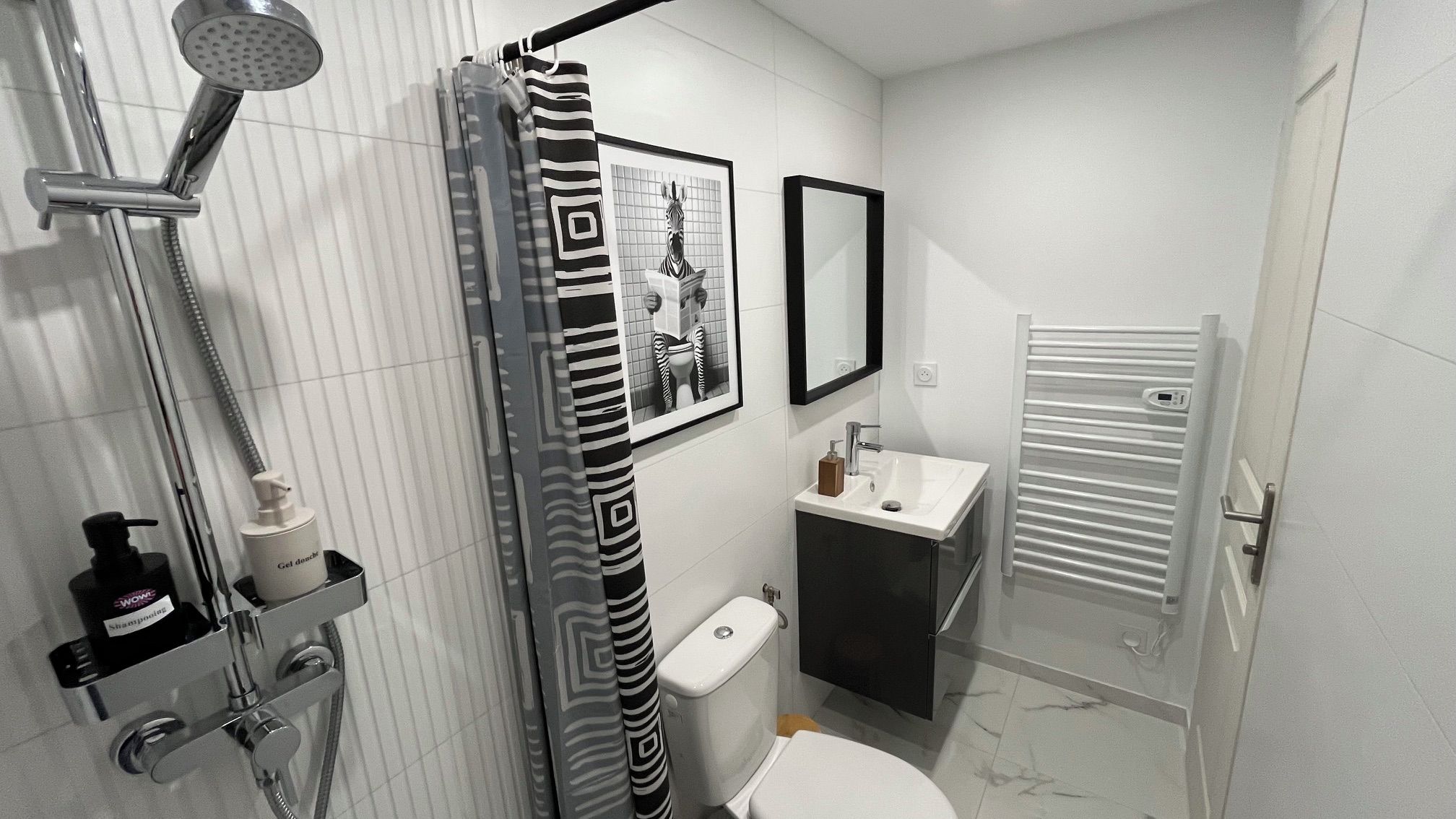 A modern bathroom with a shower, toilet, sink, and a towel rack.