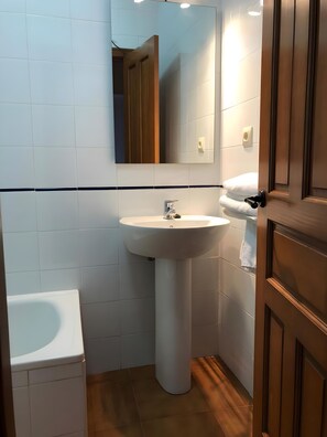 Une salle de bain avec un lavabo sur colonne, un miroir et des toilettes.