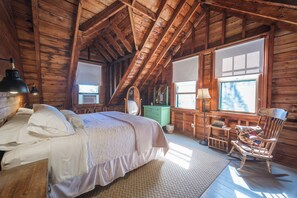 Una camera da letto mansardata accogliente con un letto grande, una poltrona a dondolo e un comò.