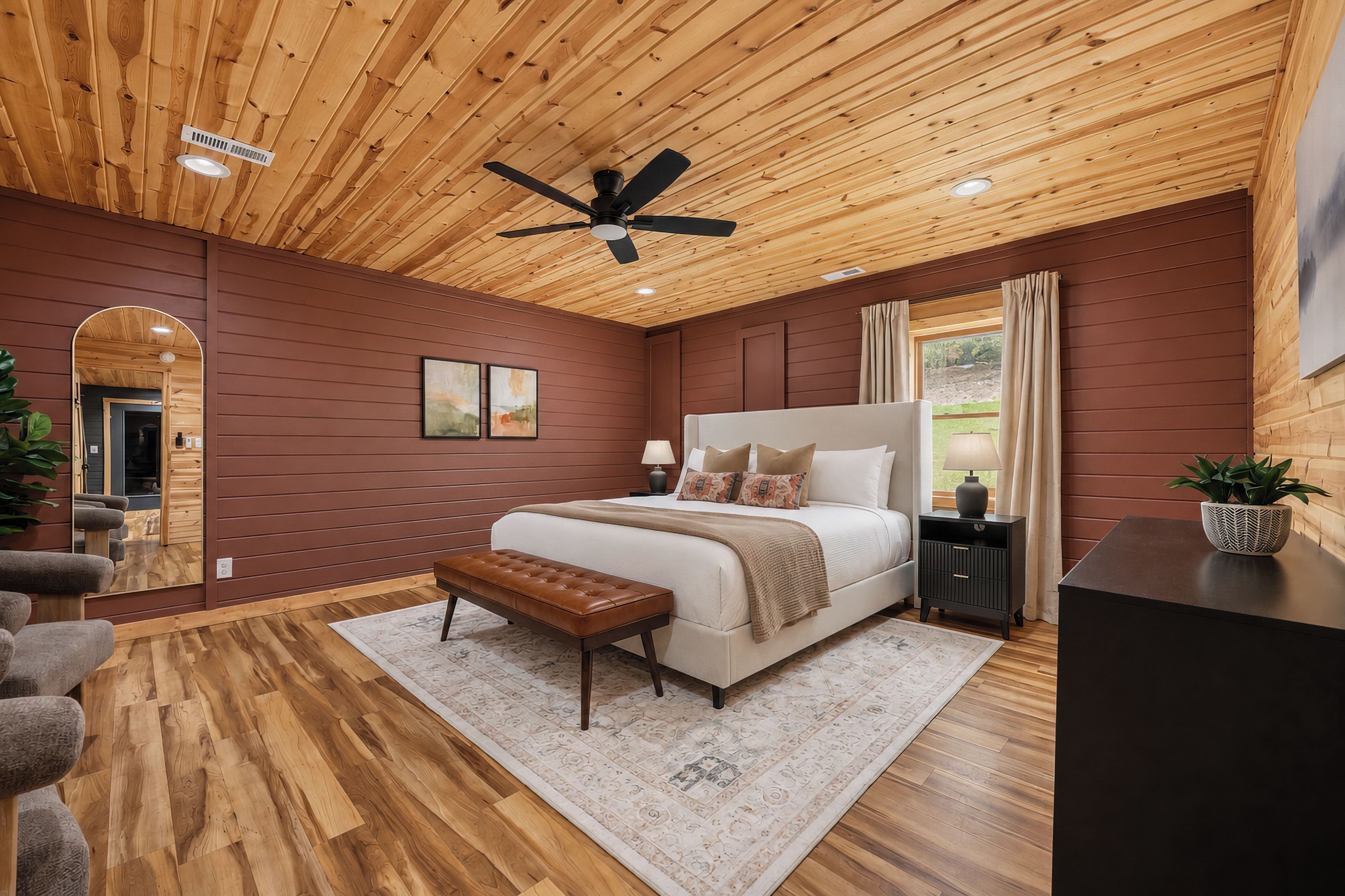 Un dormitorio con techo de madera, una cama grande, un banco, una mesita de noche y una planta en maceta.