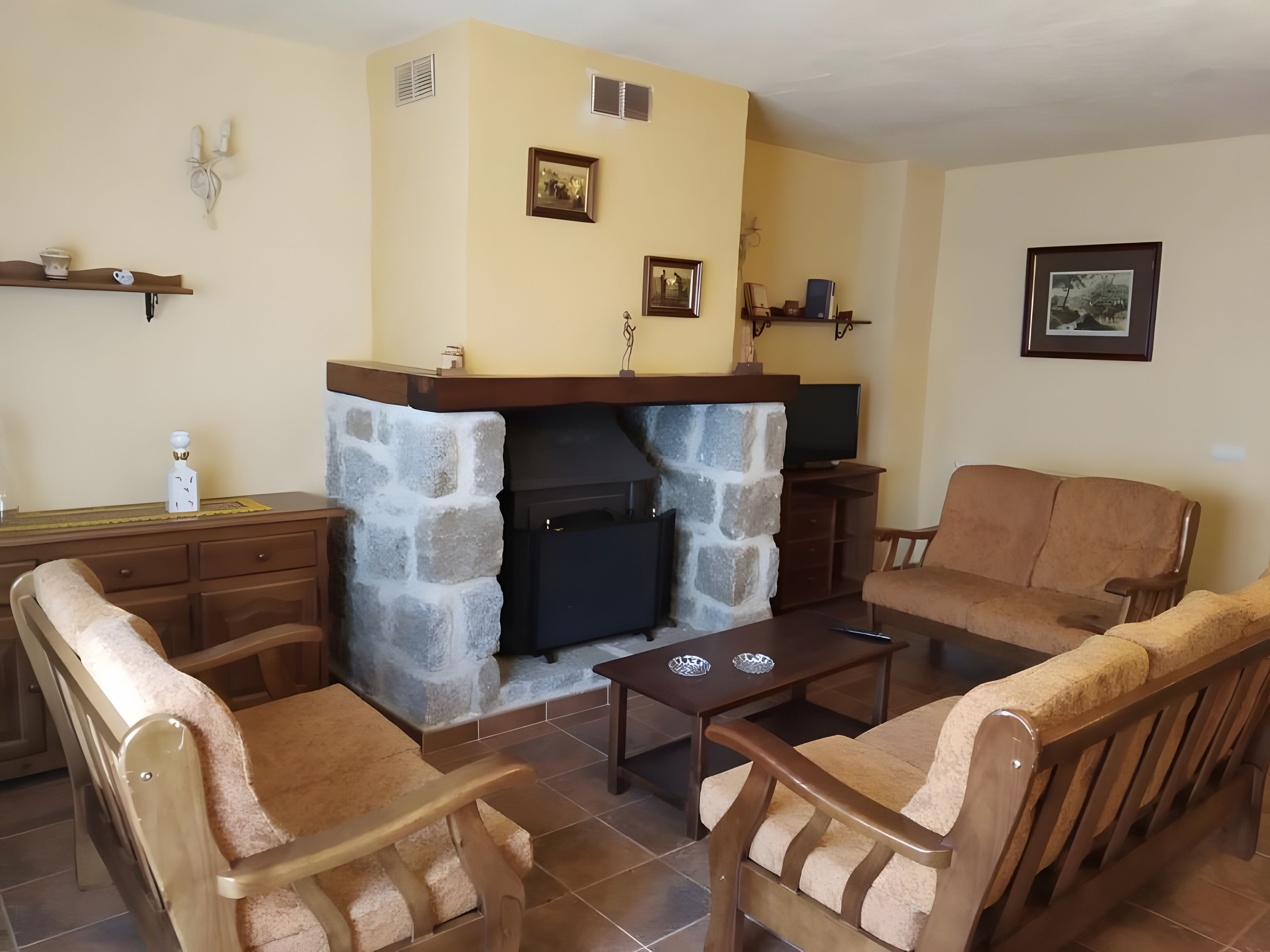 Una sala de estar con chimenea de piedra, muebles de madera y adornos en la pared.