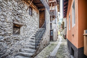 Une ruelle étroite bordée d’immeubles en pierre, avec un escalier en bois et une rambarde en métal.