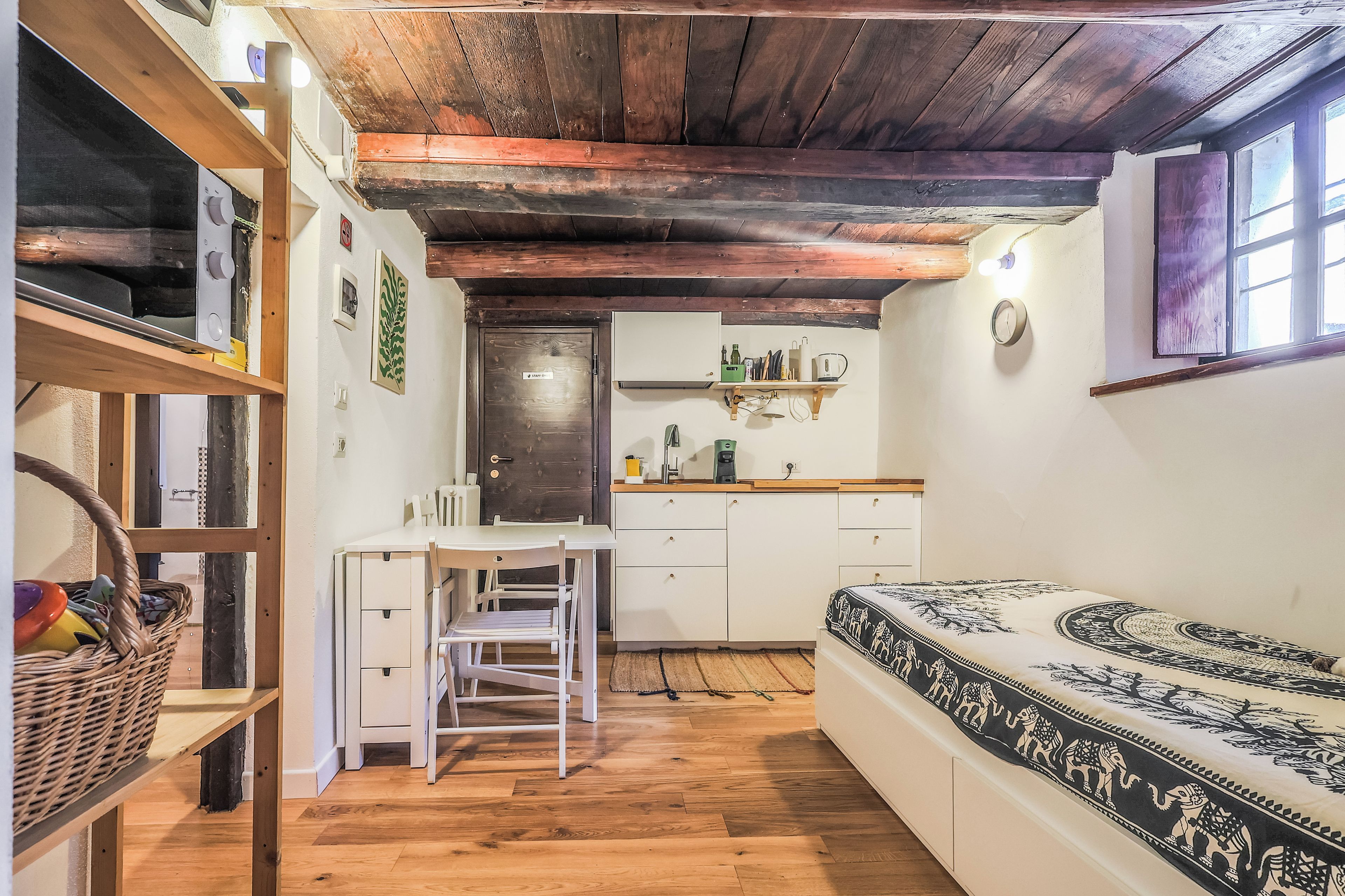 A compact room with a bed, a small kitchenette, and a dining area.