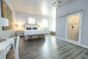 Un dormitorio moderno con una cama grande, mesitas de noche, un escritorio y una puerta corredera con un cartel.