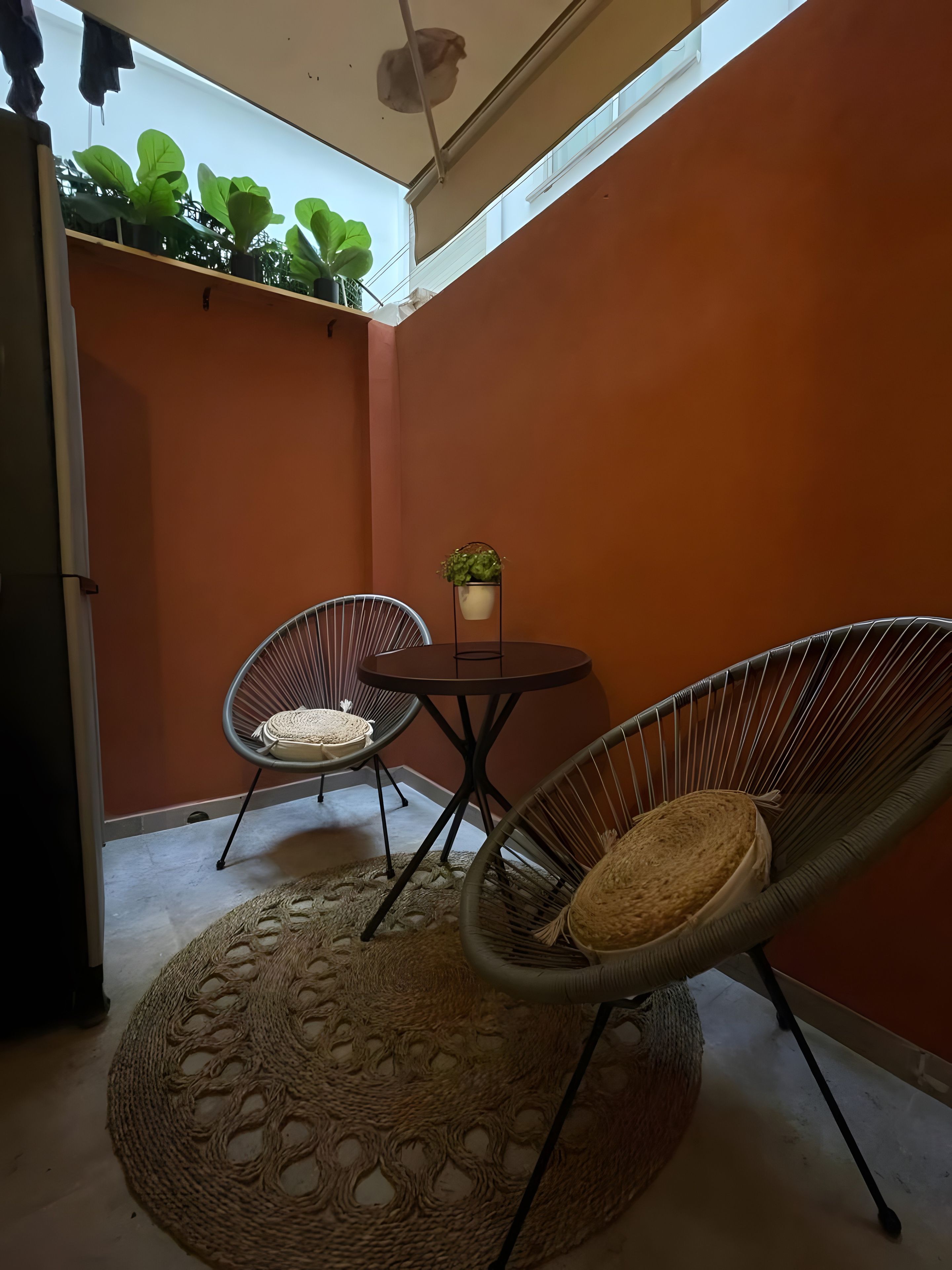 Ein kleiner Patio-Bereich mit zwei Korbstühlen, einem runden Tisch und einem Blumentopf.