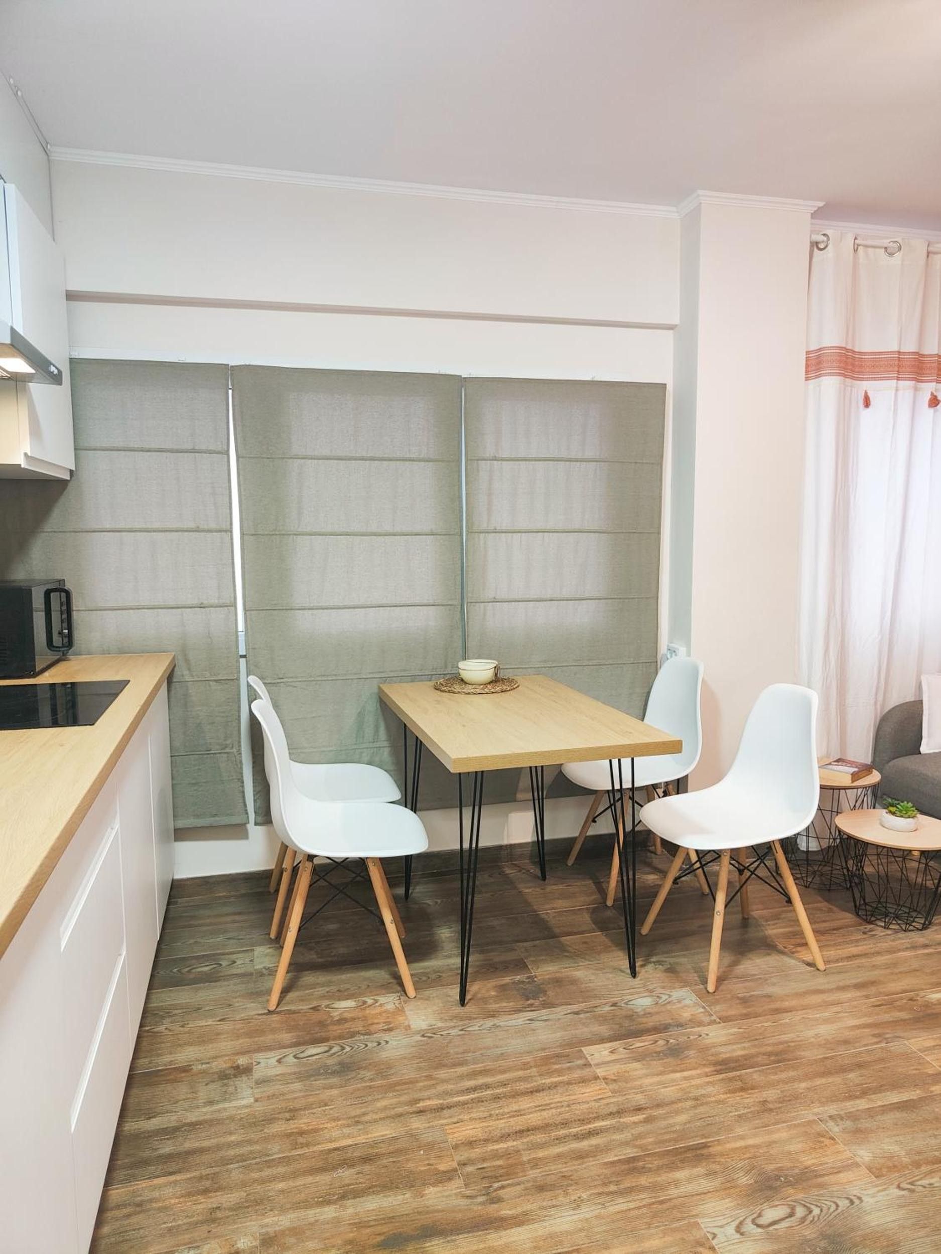 Un espace de vie compact comprenant un coin cuisine, un coin repas avec une table et des chaises, et un coin salon avec un canapé et une petite table d’appoint.