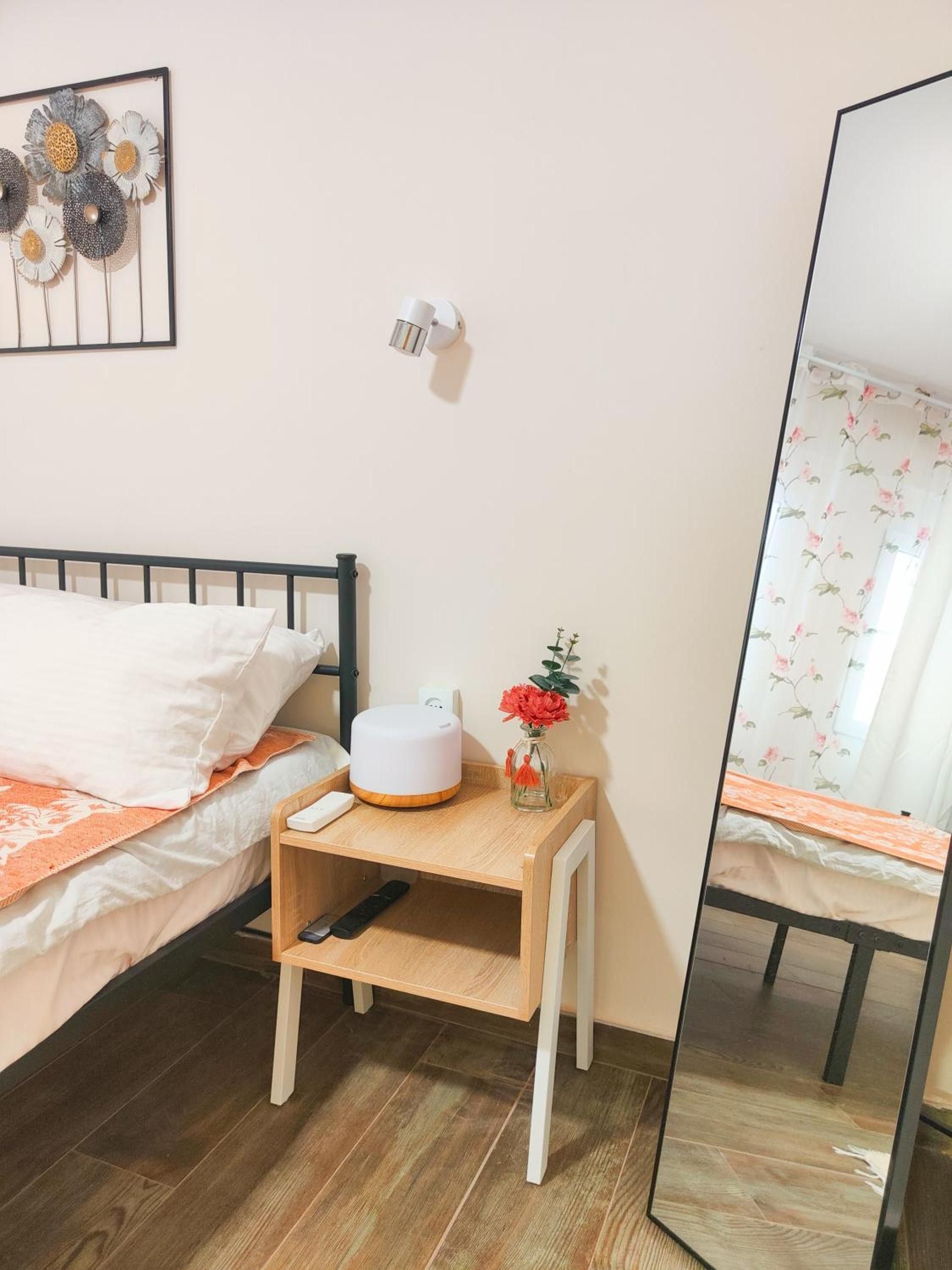 Une chambre à coucher avec un lit, une table de chevet, une lampe et un miroir.