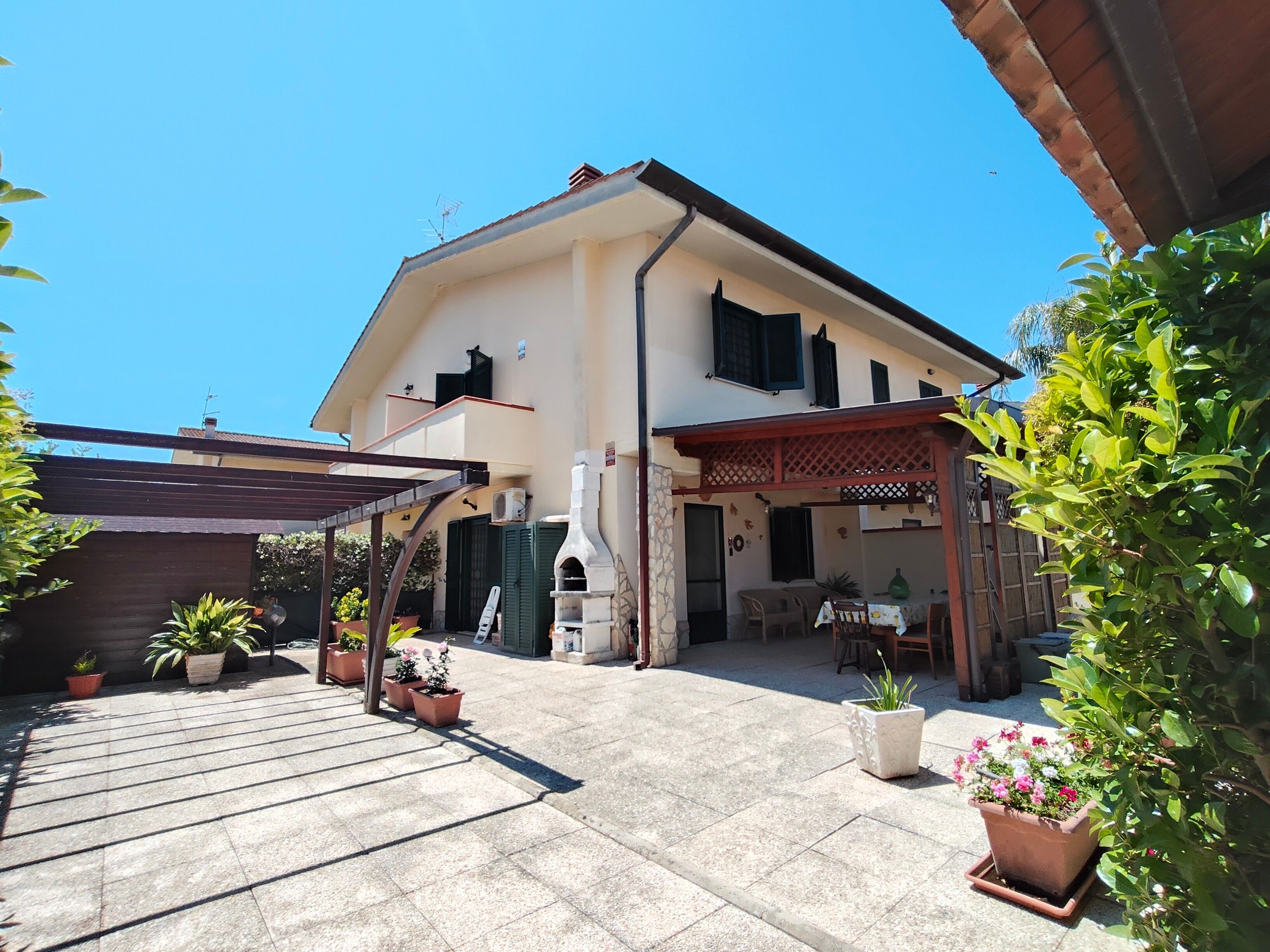 Un edificio su due piani con un patio, posti a sedere all'aperto e un forno a pietra.