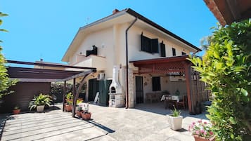 Un edificio su due piani con un patio, posti a sedere all'aperto e un forno a pietra.