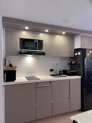 A modern kitchen with a built-in microwave, a refrigerator, and a sink. - Premium Loft La Candelaria (Bogotá)