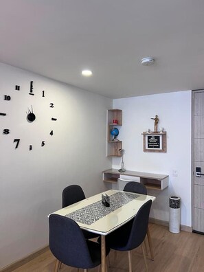 A dining area with a table, chairs, a wall clock, and a shelf with decorative items. - Premium Loft La Candelaria (Bogotá)