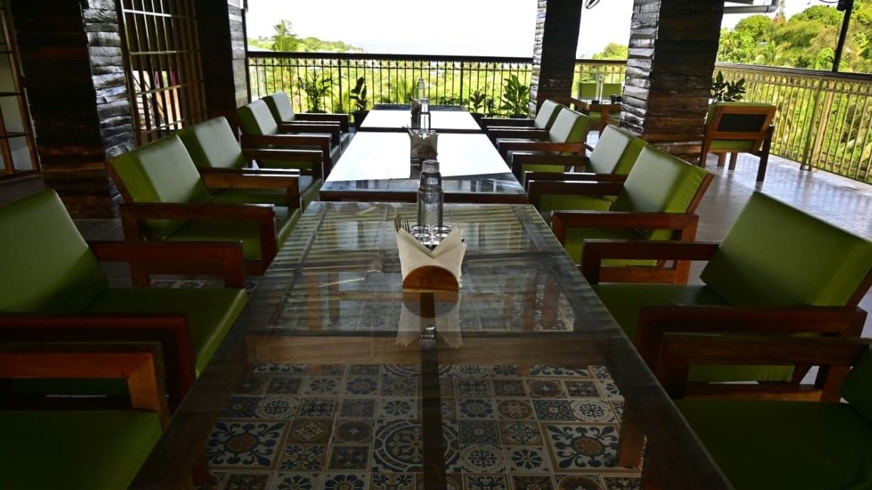 A dining area with a long table, chairs, and a view of greenery.