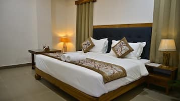 A hotel room with a large bed, two bedside tables, a nightstand, and a lamp.